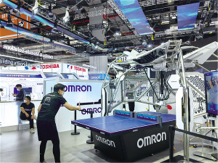 工作人員與歐姆龍第七代FORPHEUS乒乓球教練機器人進行乒乓球比賽 工作人員與歐姆龍第七代FORPHEUS乒乓球教練機器人進行乒乓球比賽